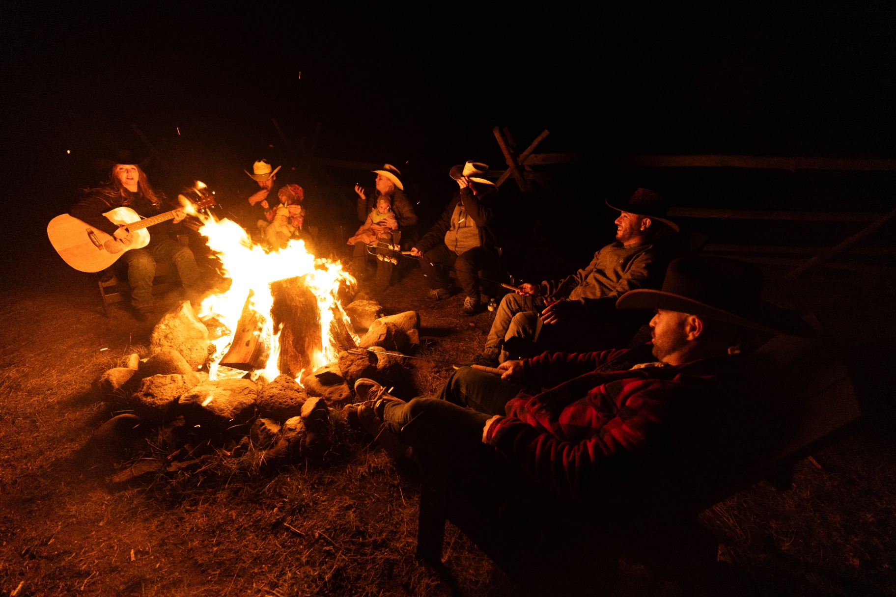 Guests gathered around a campfire at Big Bar Guest Ranch at night